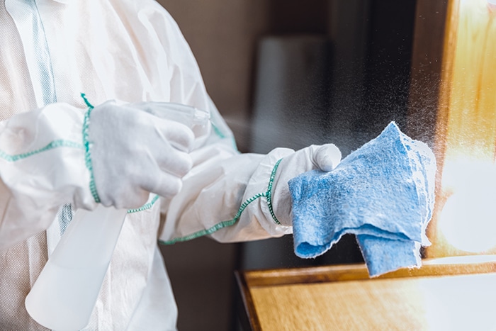 Coronavirus Pandemic. A disinfector in a protective suit and mask sprays disinfectants in the house or office Covid-19-Reinigung